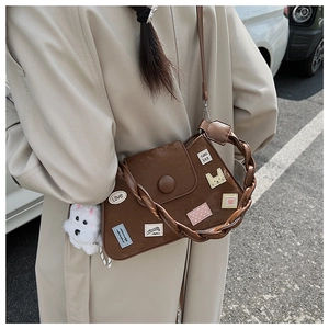 Detalle de bolso vintage de cuero marrón con parches creativos y un colgante de perro de peluche