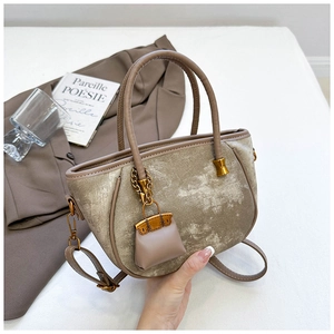 Detailed close-up of champagne velvet bucket bag with mini charm and gold hardware