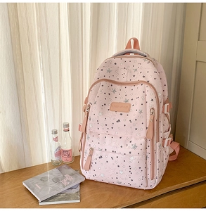 Detailed view of pink floral backpack with star prints on a wooden table setup