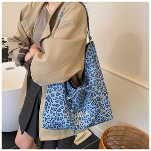 Détail du cabas en toile léopard bleu avec nœud décoratif et broderie blanche