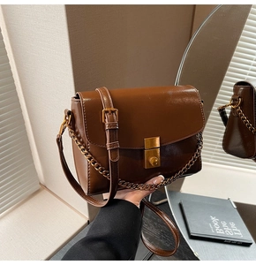 Détail du sac carré en cuir marron foncé avec fermoir doré et chaîne élégante