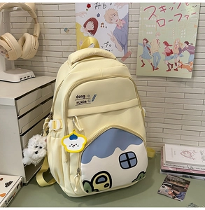Detail of a creamy yellow school backpack with house-shaped pocket and cute plush dog charm