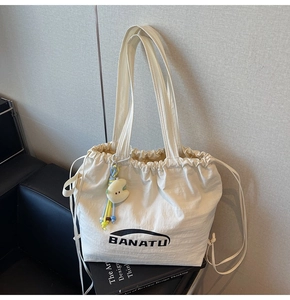 Detailansicht der beigen Nylon-Tragetasche mit Kordelzug und Plüsch-Anhänger