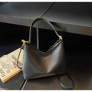 Détail du sac bandoulière noir tressé en cuir synthétique avec des finitions dorées