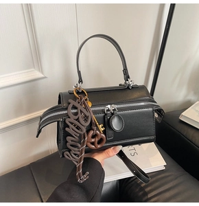 Detail view of black leather handbag with trendy Bingo charms and silver zipper
