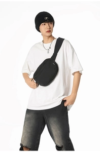 Detail of a minimalist black crossbody bag with multiple compartments on a street style model
