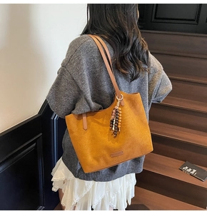 Brown faux suede tote bag with wooden bead charm worn with a cozy autumn outfit