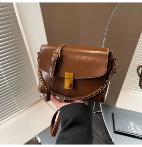 Détail d'un sac à main vintage marron avec fermoir doré et bandoulière chaîne