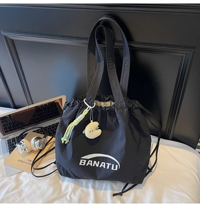 Detail der schwarzen Nylon-Kordelzug-Tasche mit BANATU-Logo und Mond-Plüsch-Anhänger
