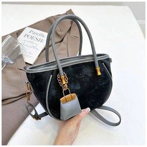 Detailed close-up of a vintage black velvet handbag with grey leather handles and gold charms