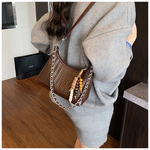 Detail of dark brown woven hobo bag with silver chain and wooden bead charm detail