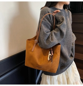 Detail of a large brown suede tote bag with ethnic beaded tassel charm for daily commute