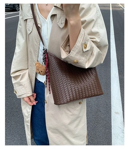 Close-up of brown woven leather hobo bag with a cute plush bear charm on strap