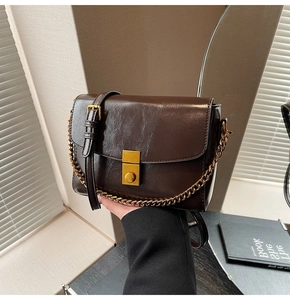 Détail du sac bandoulière vintage marron foncé avec fermoir doré et texture de la chaîne