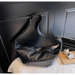 Detailed view of black crescent bag with textured stitching and adjustable strap