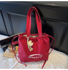 Rote Nylon-Ziehtasche mit Logo und gelbem Plüsch-Mondanhänger in der Detailansicht