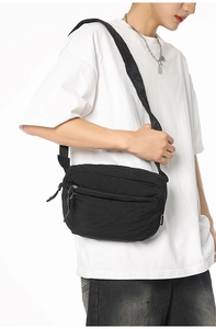 Detail of minimalist black nylon crossbody bag with zipper pocket and adjustable strap