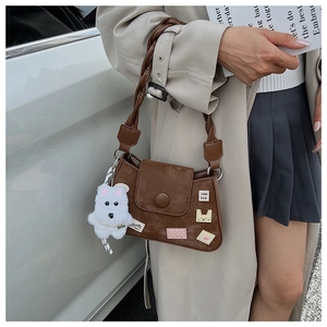 Primer plano de bolso bandolera marrón retro con parches bordados y dije de peluche