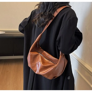 Close-up of brown leather crescent bag with decorative stitching and metal zipper