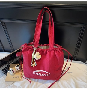 Detailaufnahme einer roten Nylon-Kordelzugtasche mit Plüsch-Anhänger auf einem Schreibtisch