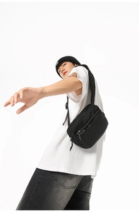 Detail of minimalist black nylon crossbody bag with multi-compartments and matte finish