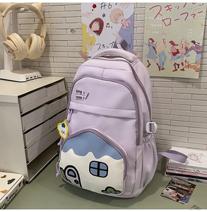 Detailed view of lavender school backpack with blue cartoon house pocket and charm