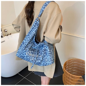 Détail du sac cabas bleu à motif léopard avec broderie blanche porté par un mannequin
