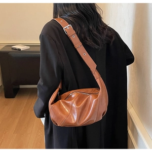 Detail view of the adjustable strap and silver metal buckle on a brown leather crescent bag