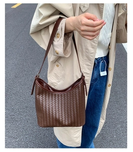 Brown woven leather bucket bag worn with a beige trench coat for a stylish daily commute