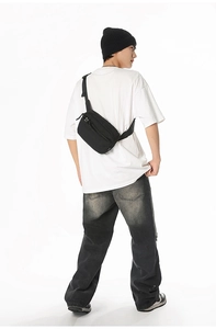 Adjustable black nylon chest bag with multiple zip compartments on male model