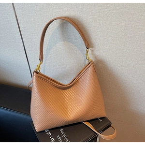 Détail du sac hobo marron tissé montrant la texture cuir et crochets dorés
