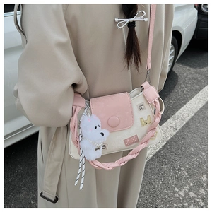 Detalle del bolso tipo cubo de retazos rosa y blanco con parche Good Luck y peluche
