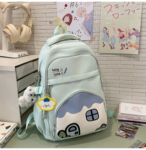 Close-up of mint green school backpack featuring house prints and plush dog charm