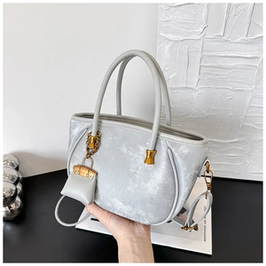 Macro shot of silver metallic leather bucket bag with a miniature handbag charm