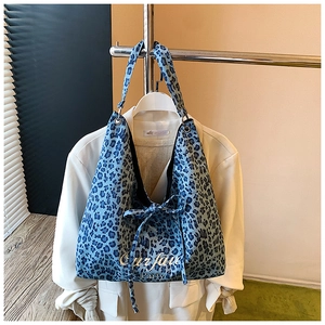 Détail du sac cabas bleu à motif léopard avec nœud décoratif et broderie de la marque
