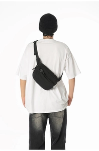 Rear view of black nylon crossbody bag with adjustable wide strap on model