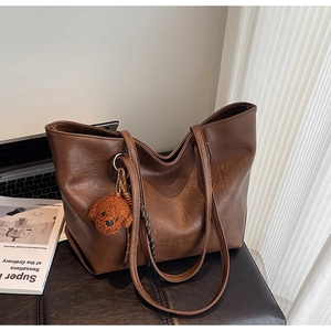 Detailed texture of brown faux leather tote bag with stylish teddy bear keychain