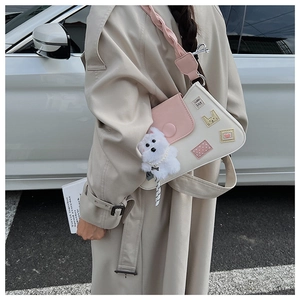 Detalle de bolso tipo cubo con parches de dibujos y amuleto de perro de peluche