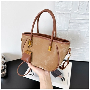 Detailed close-up of warm brown velvet tote bag with leather trim and gold hardware