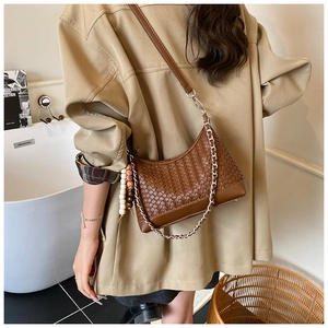 Detail of a brown woven crossbody bag with metal chain strap and wooden bead charm