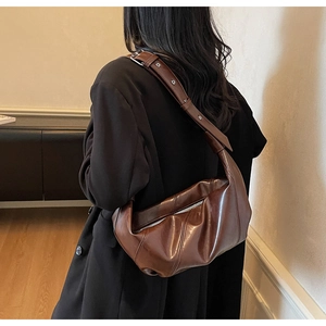 Detail view of the deep brown glossy leather moon bag with wide adjustable shoulder strap