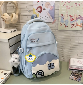 Detail of light blue school backpack featuring cute house graphics and plush dog pendants