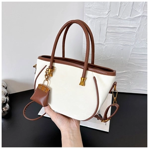 Close-up of contrast color handbag with brown leather trim and mini pouch charm