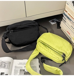 Close-up of nylon crossbody bags in black and neon green with wide adjustable shoulder straps
