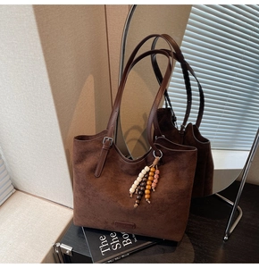Detail of dark brown suede tote bag with wood bead tassel and adjustable shoulder strap