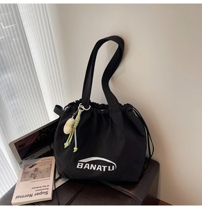 Detail einer großen schwarzen Nylon-Tragetasche mit BANATU-Logo und süßem Plüsch-Anhänger