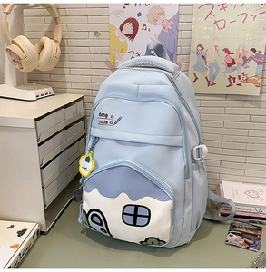 Detail of light blue student backpack with cartoon house print and cloud charm accessory