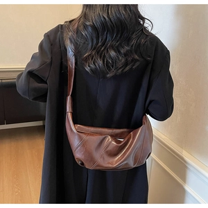 Detailed back view of a large dark brown crescent leather shoulder bag worn by a model