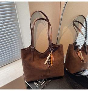 Deep brown suede tote bag detail featuring silver hardware and decorative wooden beads