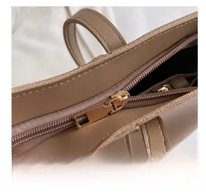 Détail montrant la fermeture éclair en métal doré et la couture sur le sac en cuir kaki